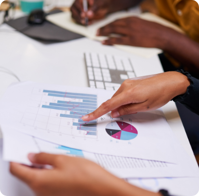 Hand pointing at charts and graphs printed on a piece of paper